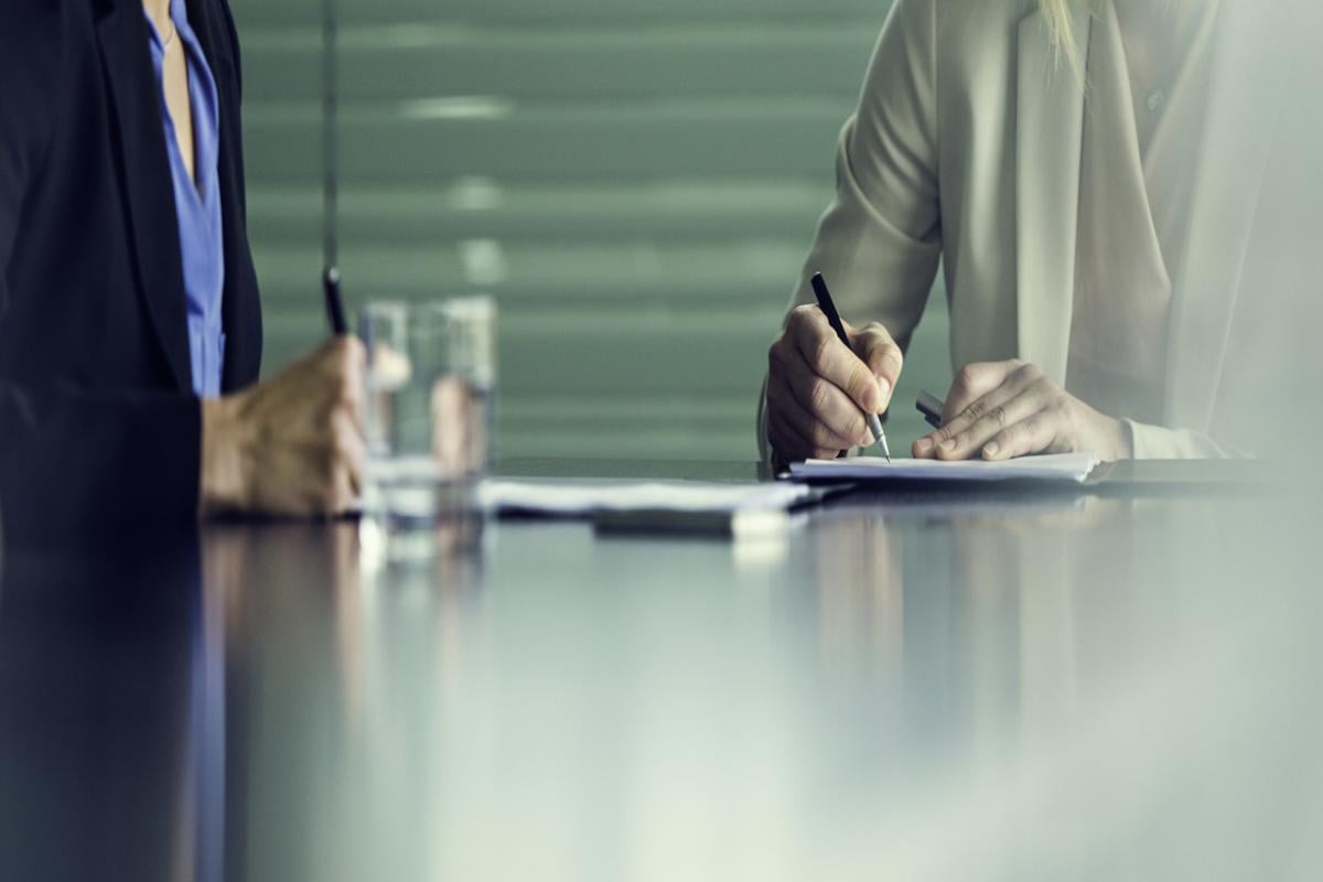 Two people making notes while reviewing a contract.